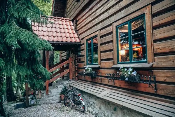 Drewniana chata z kwiatami w oknach i rowerem przy schodach. Idealne romantyczne miejsca Dolny ÅlÄsk na wypoczynek.